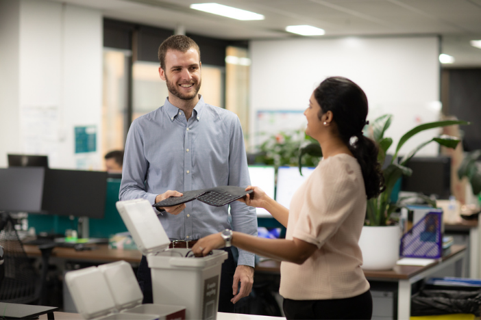 Two office workers passing a keyboard